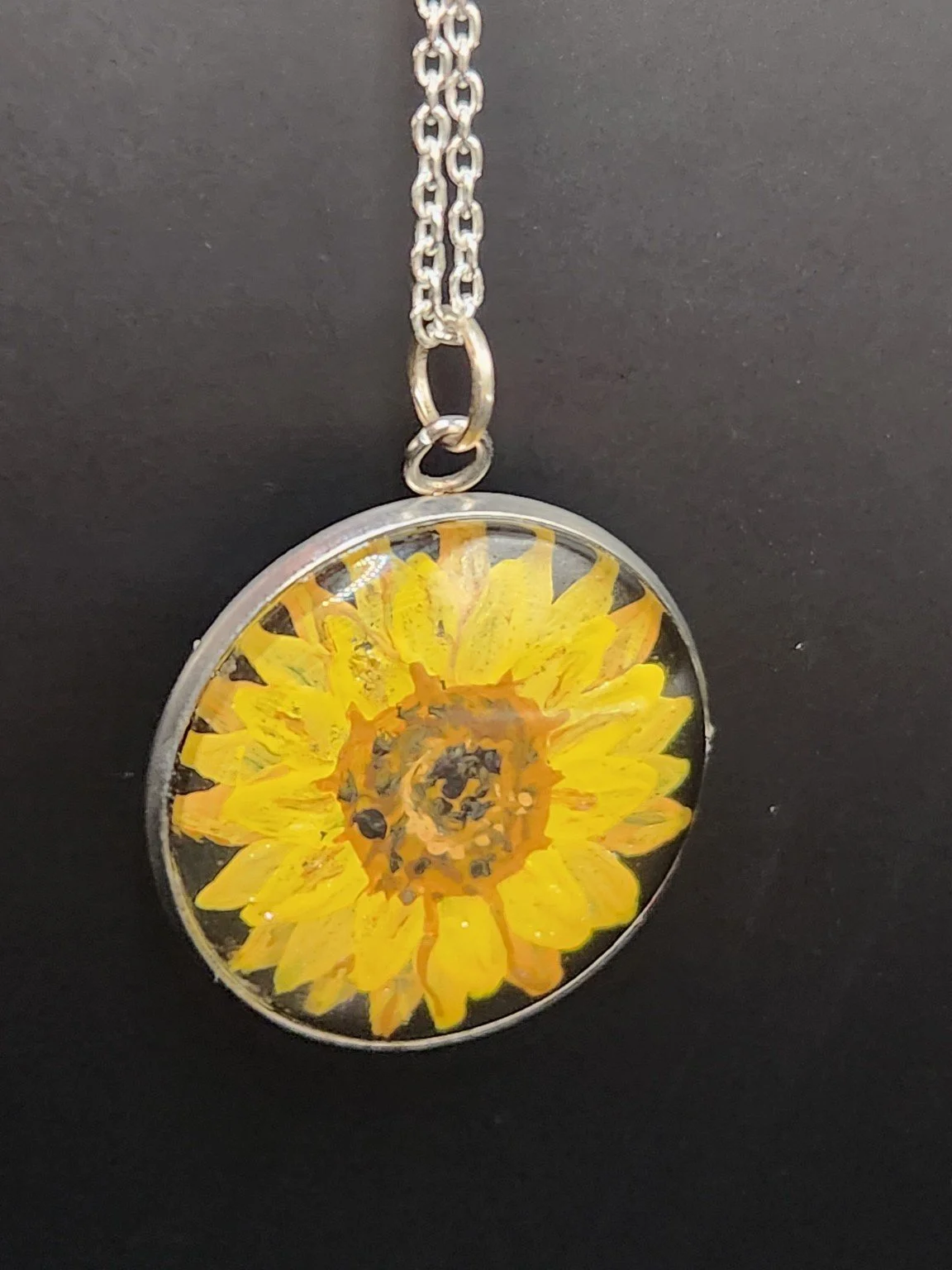 Yellow sunflower art pendant hanging from a silver-tone chain. Chain not included.