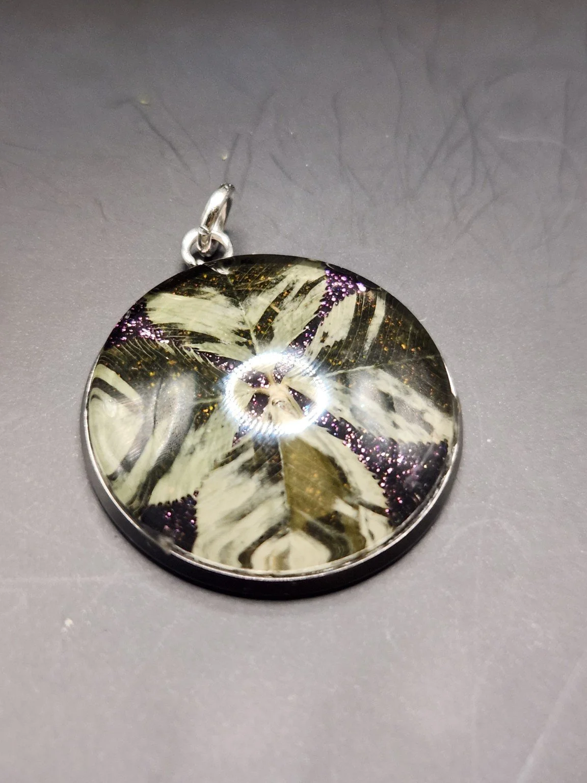 Perfectly Imperfect I002: real four-leaf clover pendant with purple glitter and feather-like translucent leaf patterns, close-up on gray.