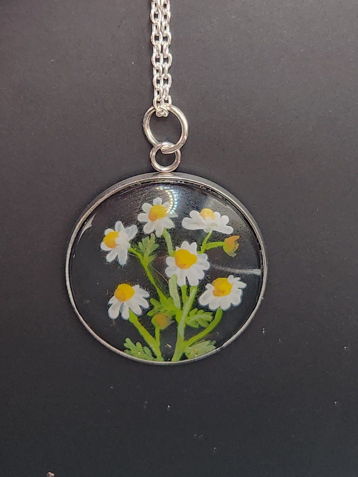 Chamomile flower art pendant shown on a silver-tone chain against a dark background. Chain not included.