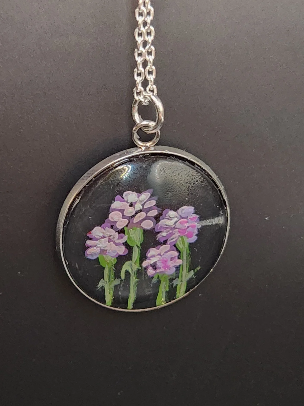 Pink and purple carnation flower art pendant shown on a silver-tone chain against a dark background. Chain not included.