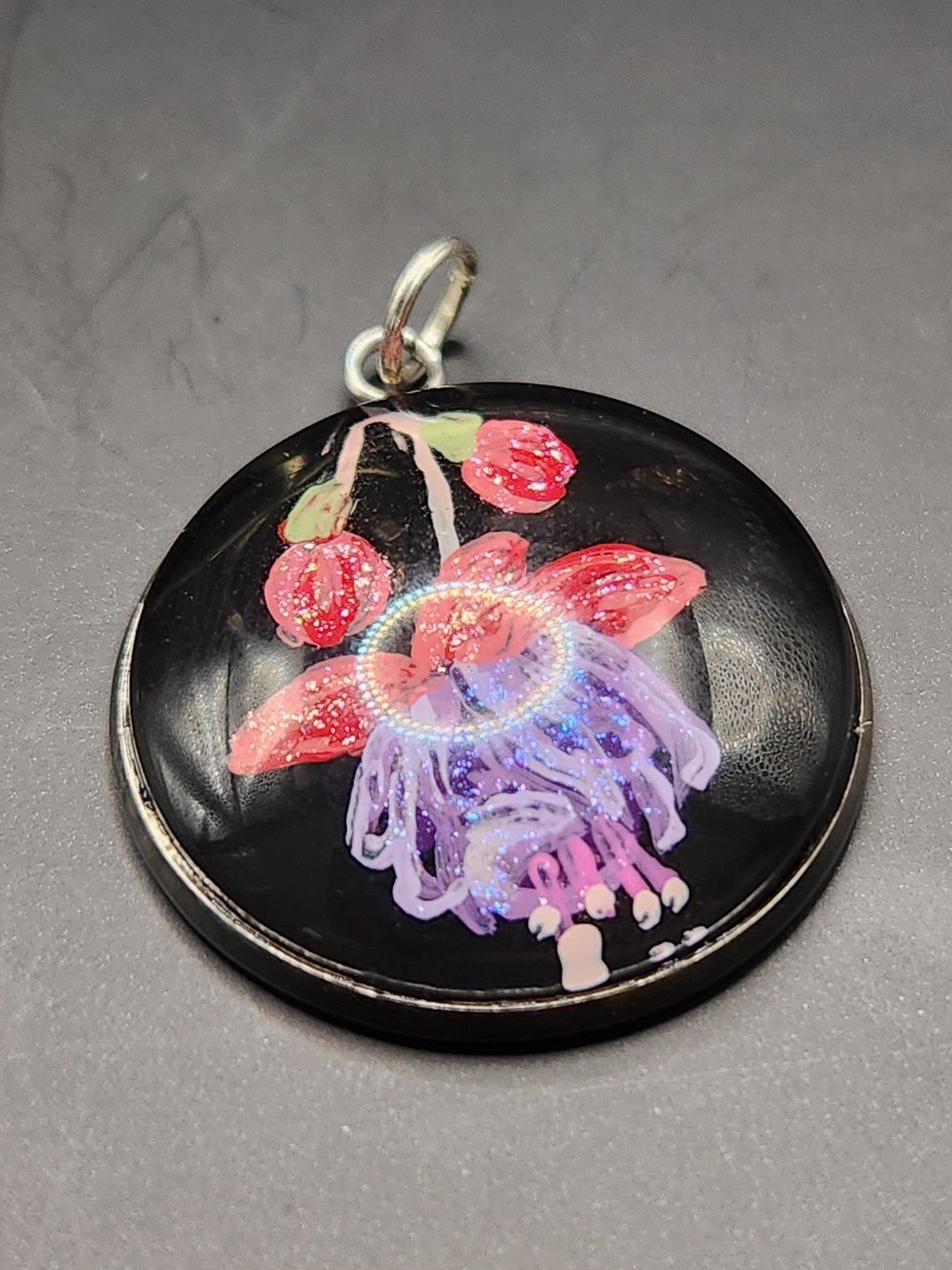 Red and purple fuchsia flower art pendant with dangling petals and shimmering glitter accents.