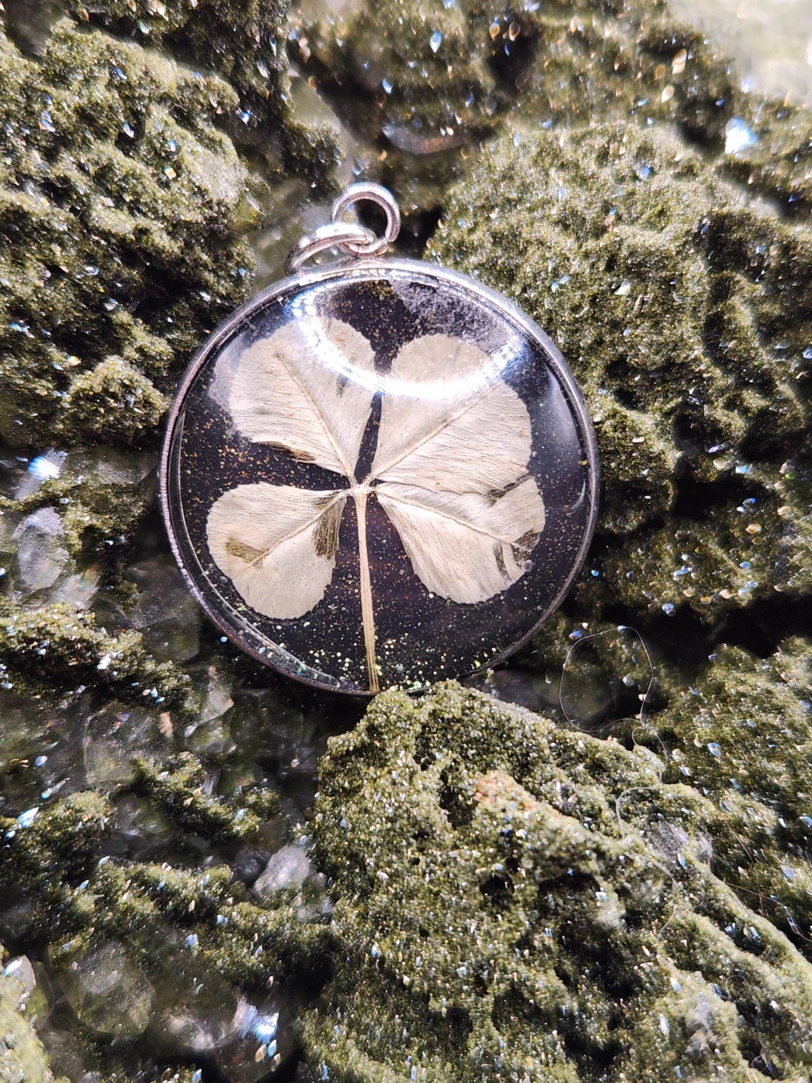 Pristine P001: real four-leaf clover pendant with green glitter, shown on a crystal display. Display not included.