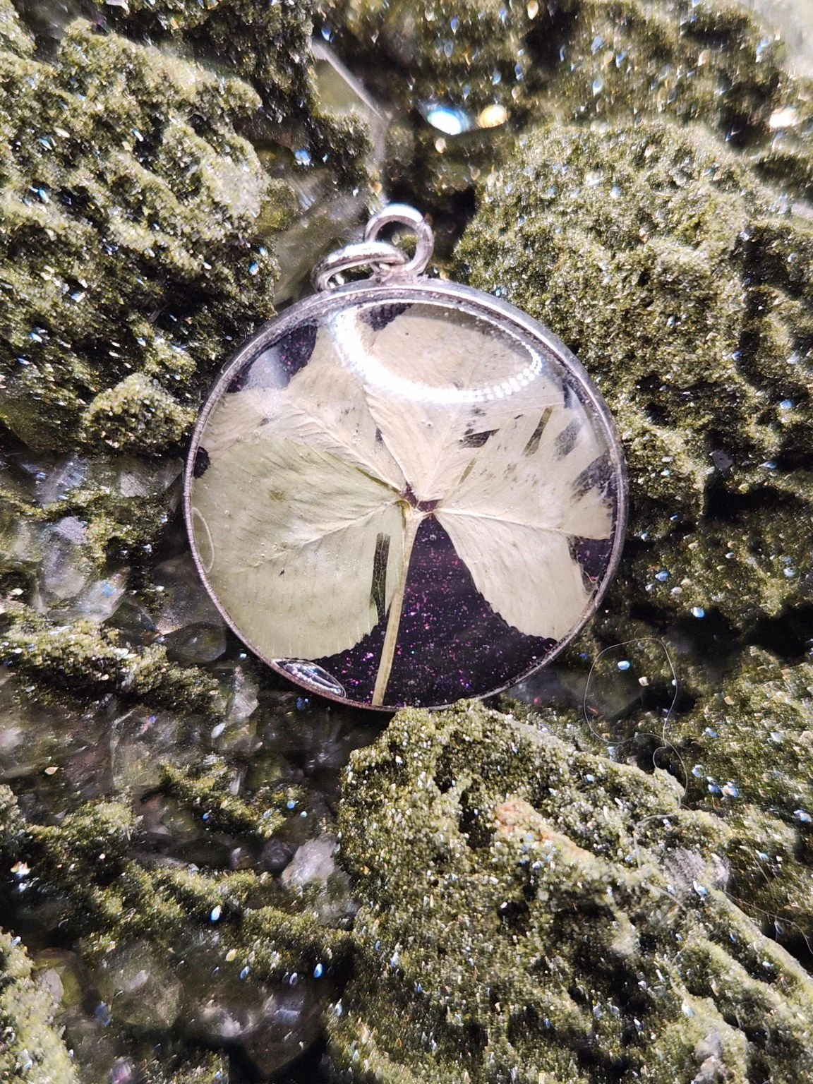 Naturally Unique N001: real four-leaf clover pendant with purple glitter on a crystal display. Display not included.