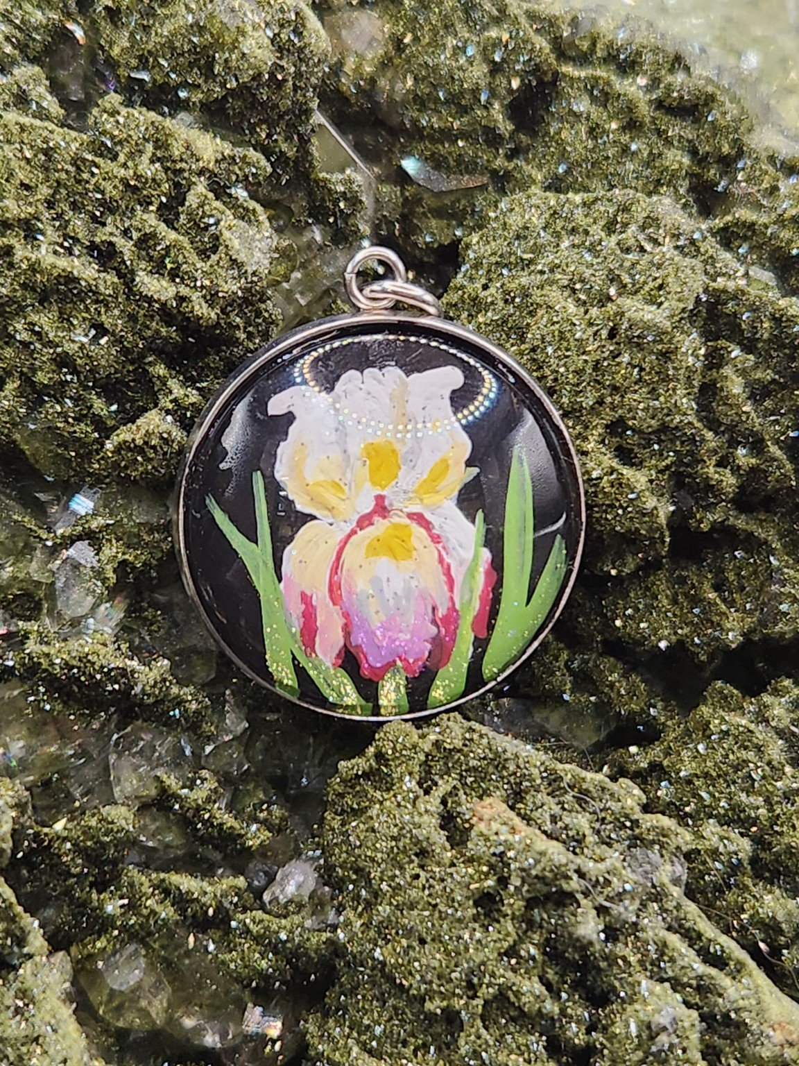 Iris flower art pendant displayed among sparkling green crystals. Crystal display and props not included.