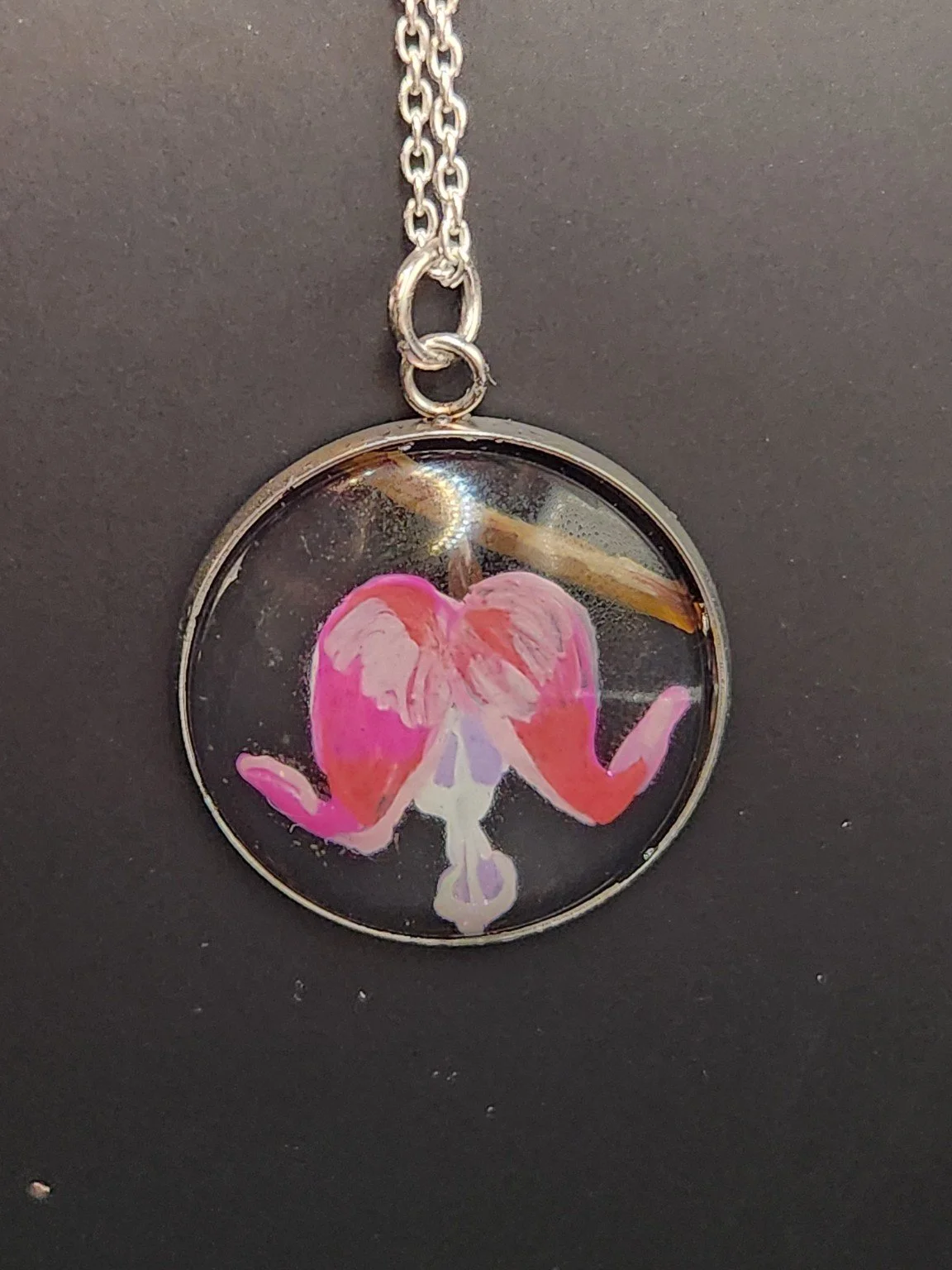 Pink bleeding heart flower art pendant hanging from a silver-tone chain. Chain not included.