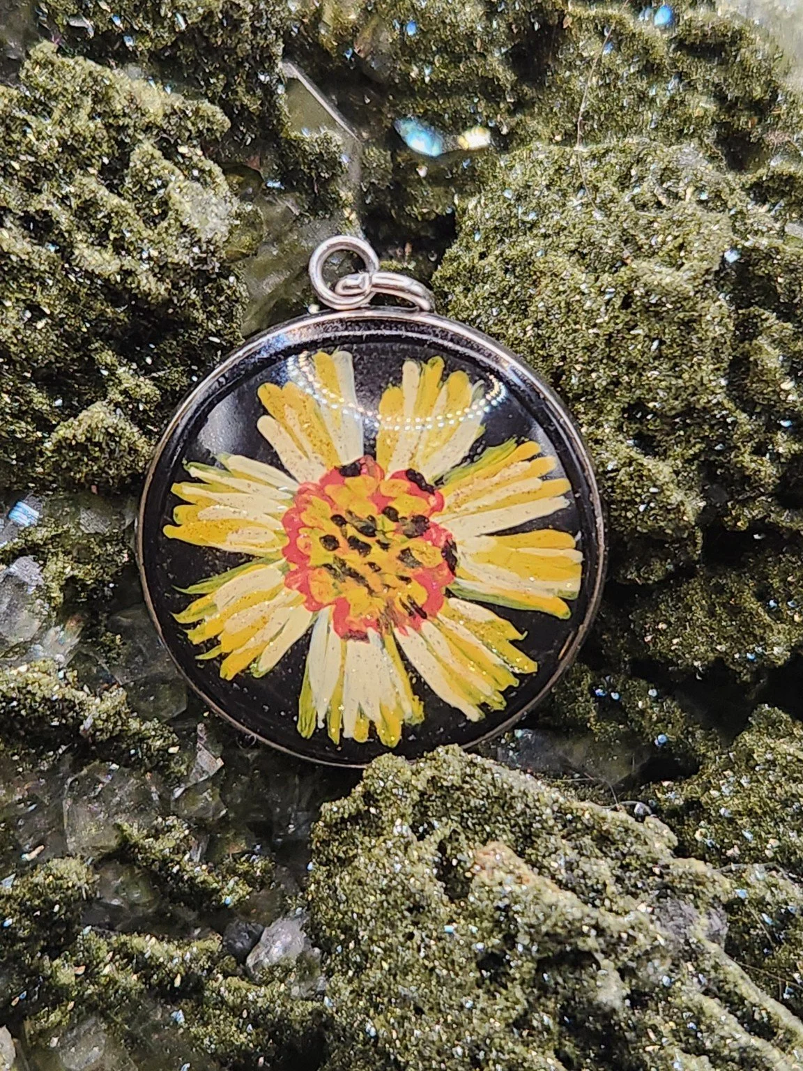 Yellow coreopsis flower art pendant nestled in a sparkling green crystal display. Crystal and display props not included.