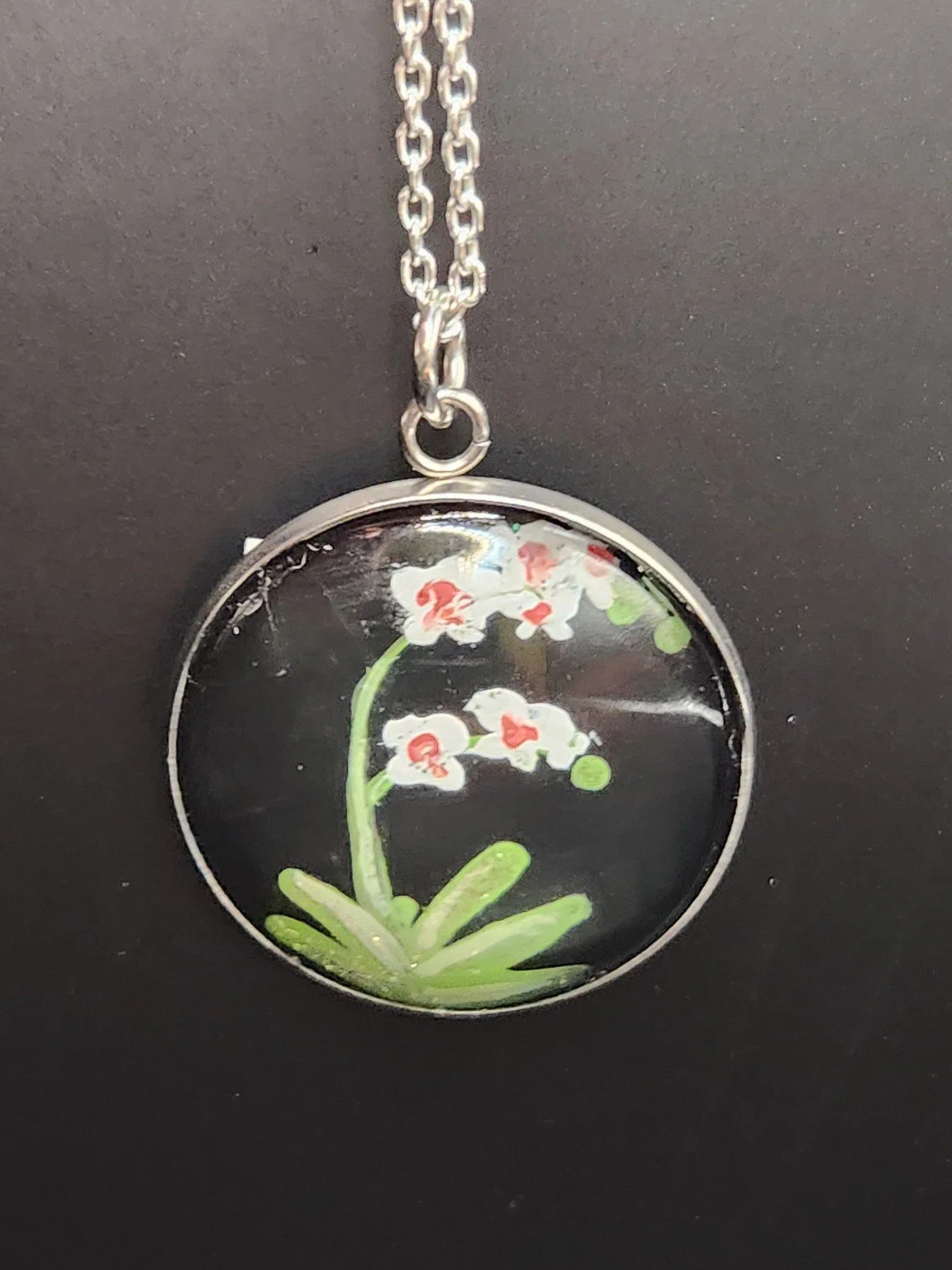 Orchid flower art pendant hanging from a silver-tone chain. Chain not included.