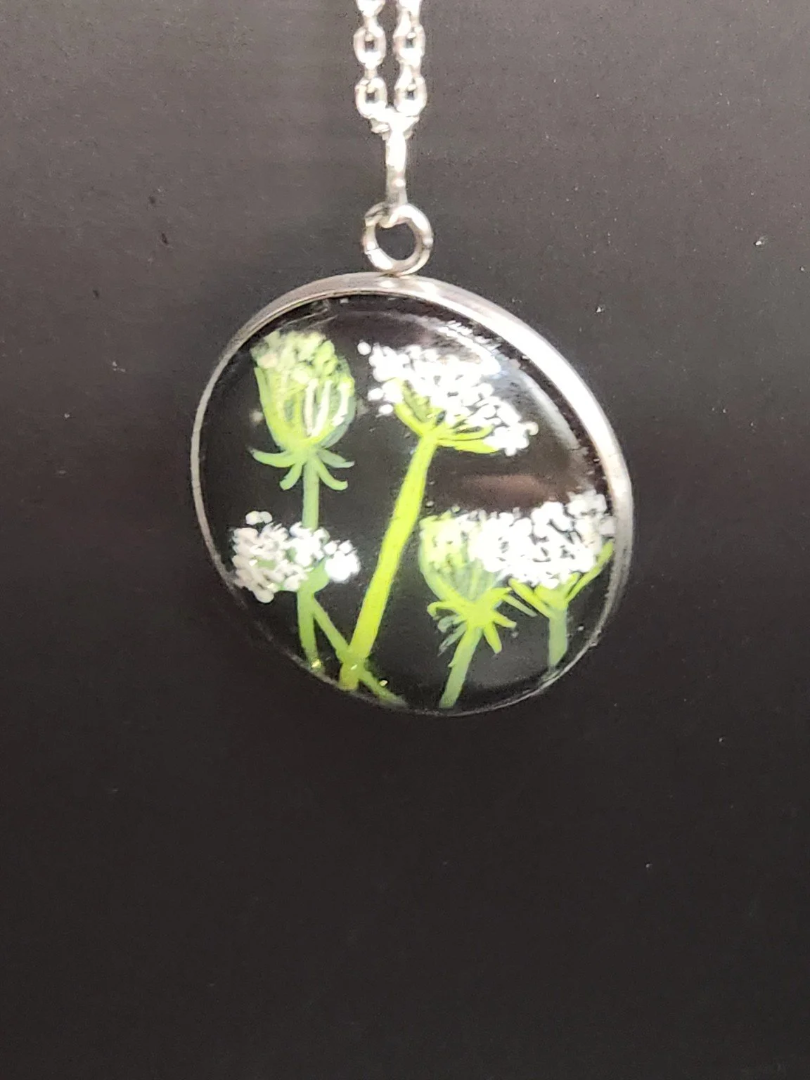 Queen Anne’s lace flower art pendant shown on a silver-tone chain against a dark background. Chain not included.