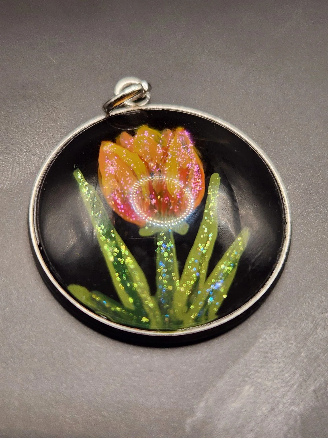 Yellow and orange tulip art pendant with sparkling glitter details on a dark background.