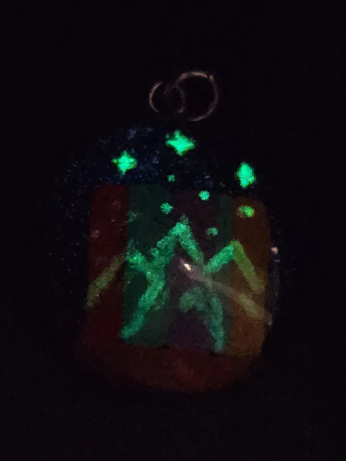 Darkened view of the ACOTAR-inspired pendant showing Velaris mountains and three stars glowing green.