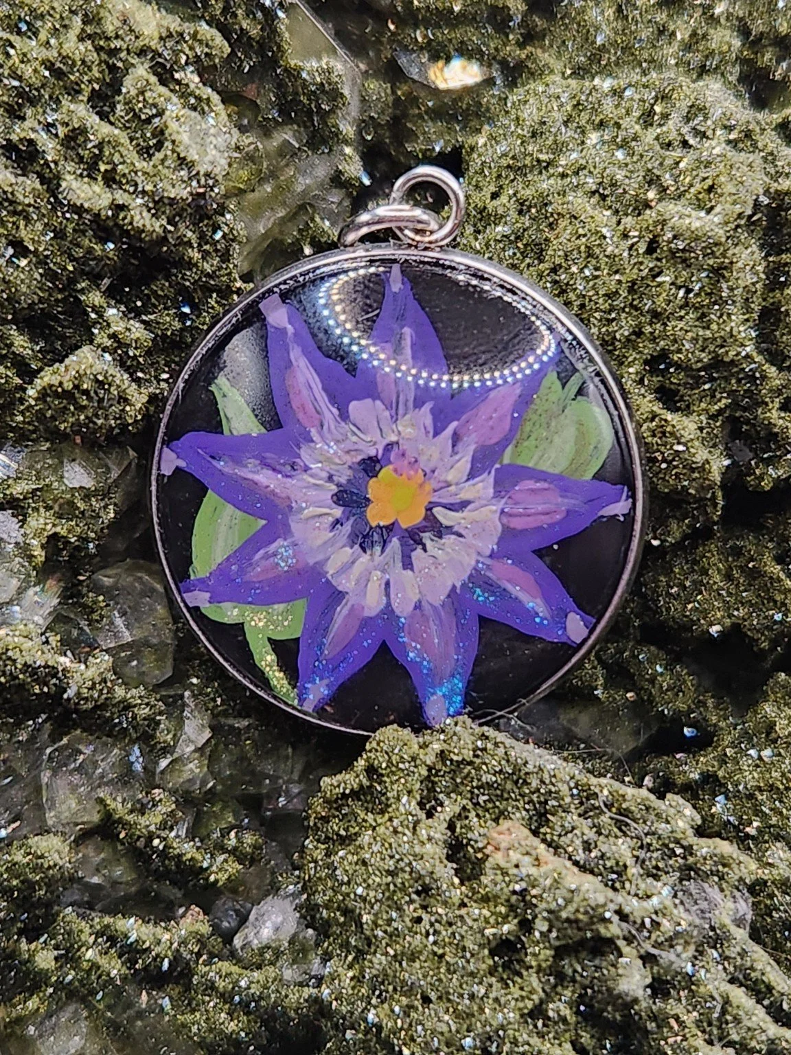 Purple clematis flower art pendant among sparkling green crystals. Crystal display and props not included.