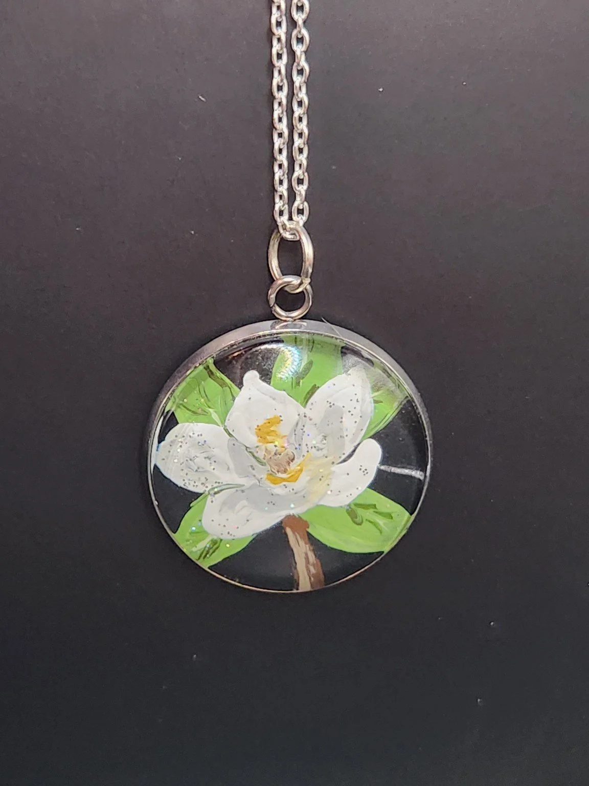 White magnolia flower art pendant hanging from a silver-tone chain. Chain not included.