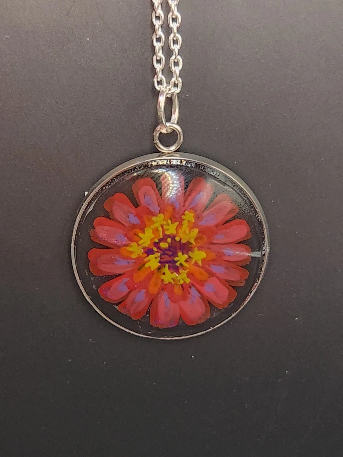Zinnia pendant shown on a chain for styling; chain not included.