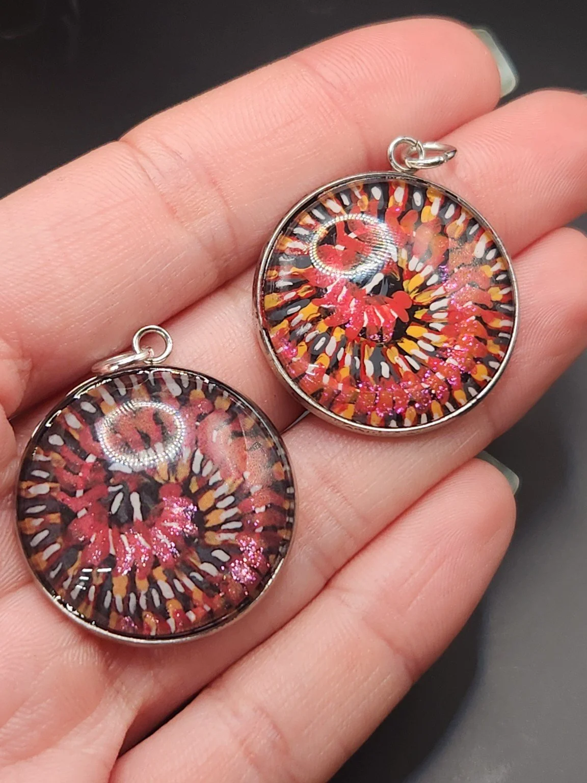 Millipede Design 1 pendant comparison held in a hand: the hand-painted original is at the top right, and the printed reproduction is at the bottom left.