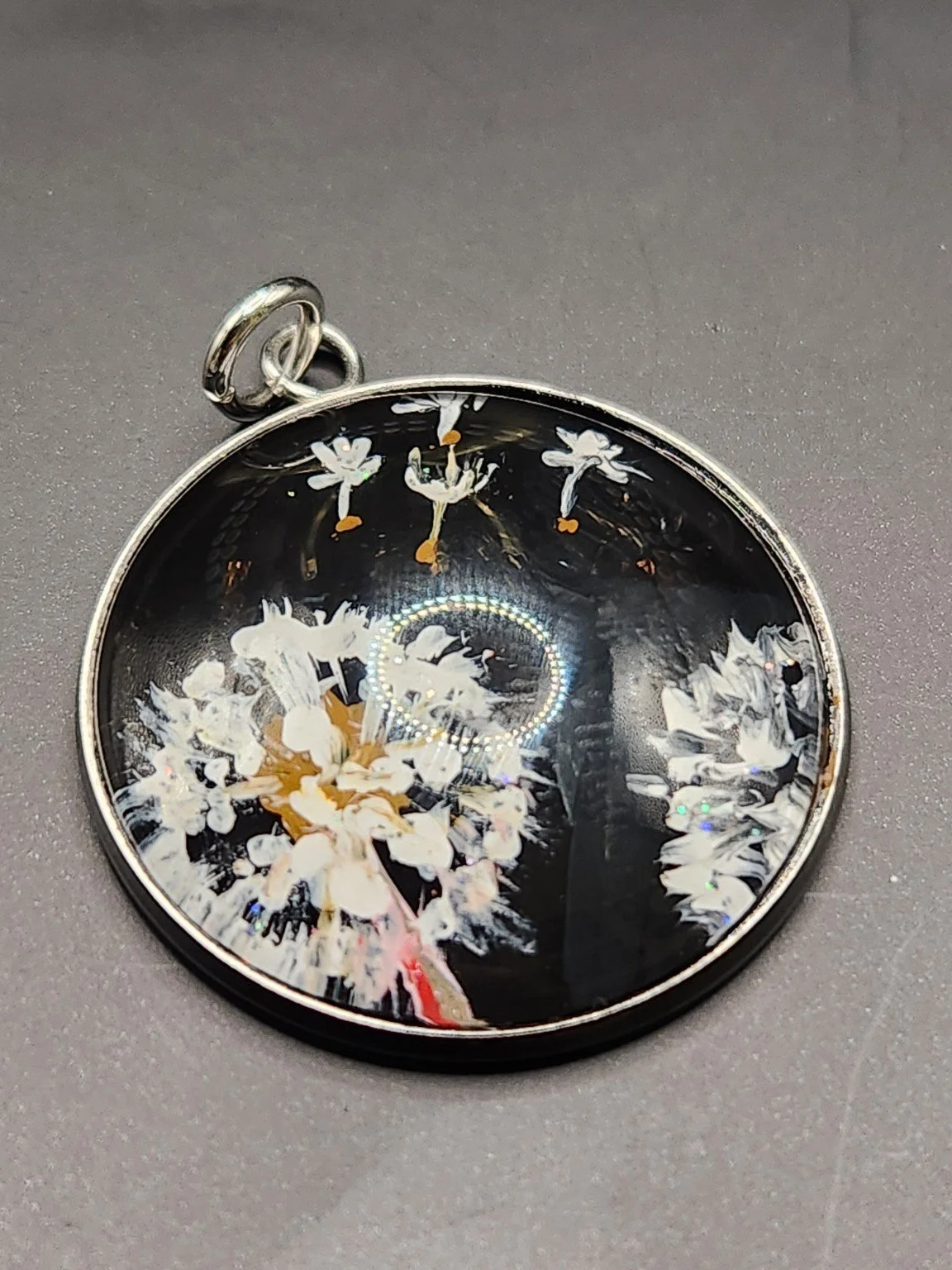 Dandelion Wish art pendant with white seed heads, drifting seeds, and glitter accents against a black background in a silver-tone bezel.
