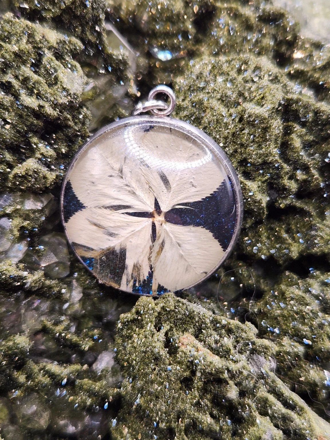 Naturally Unique N002: real four-leaf clover pendant with blue glitter on a crystal display. Display not included.