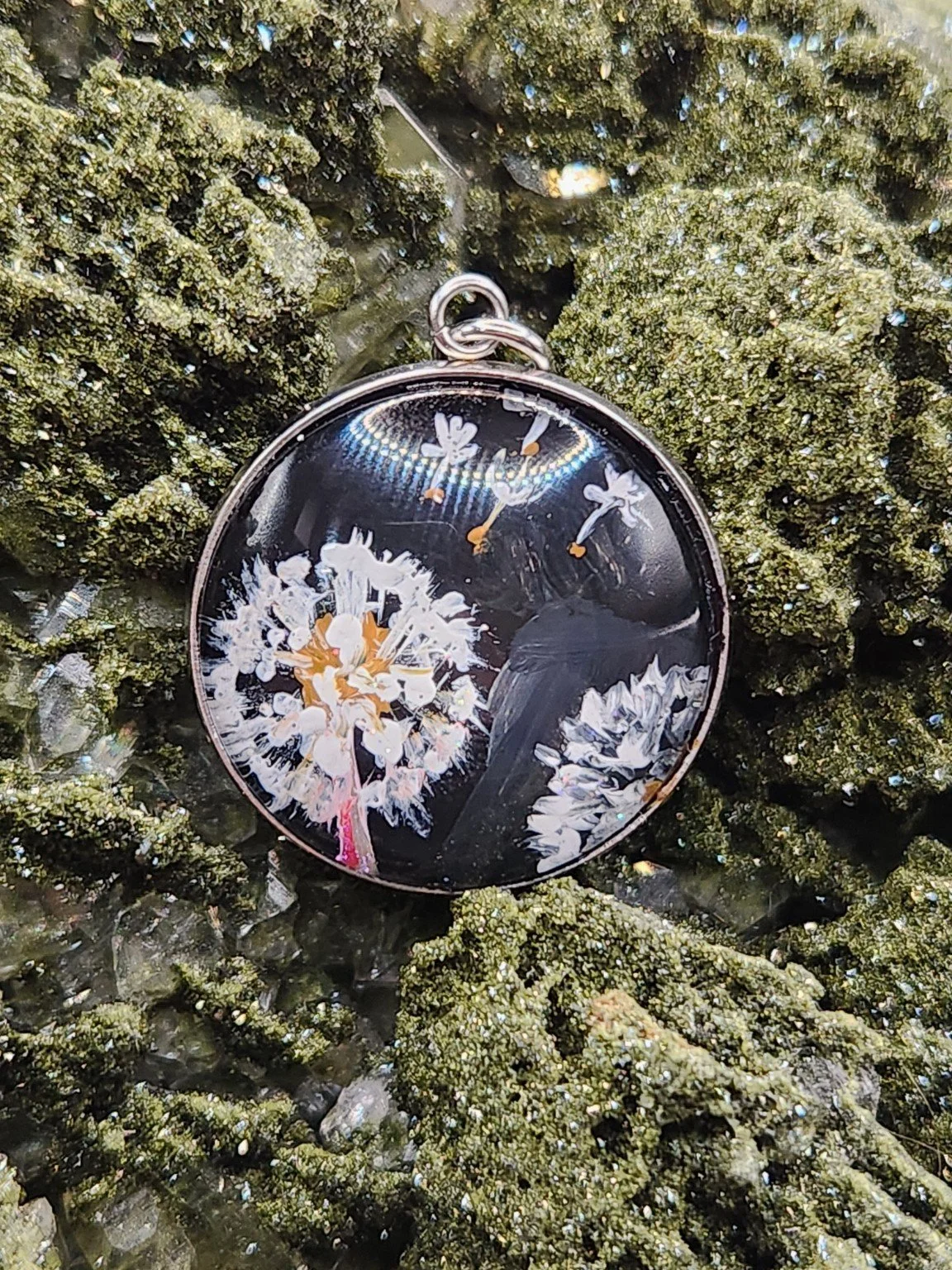 Dandelion Wish art pendant with white seed heads nestled in a sparkling green crystal display. Crystal and display props not included.