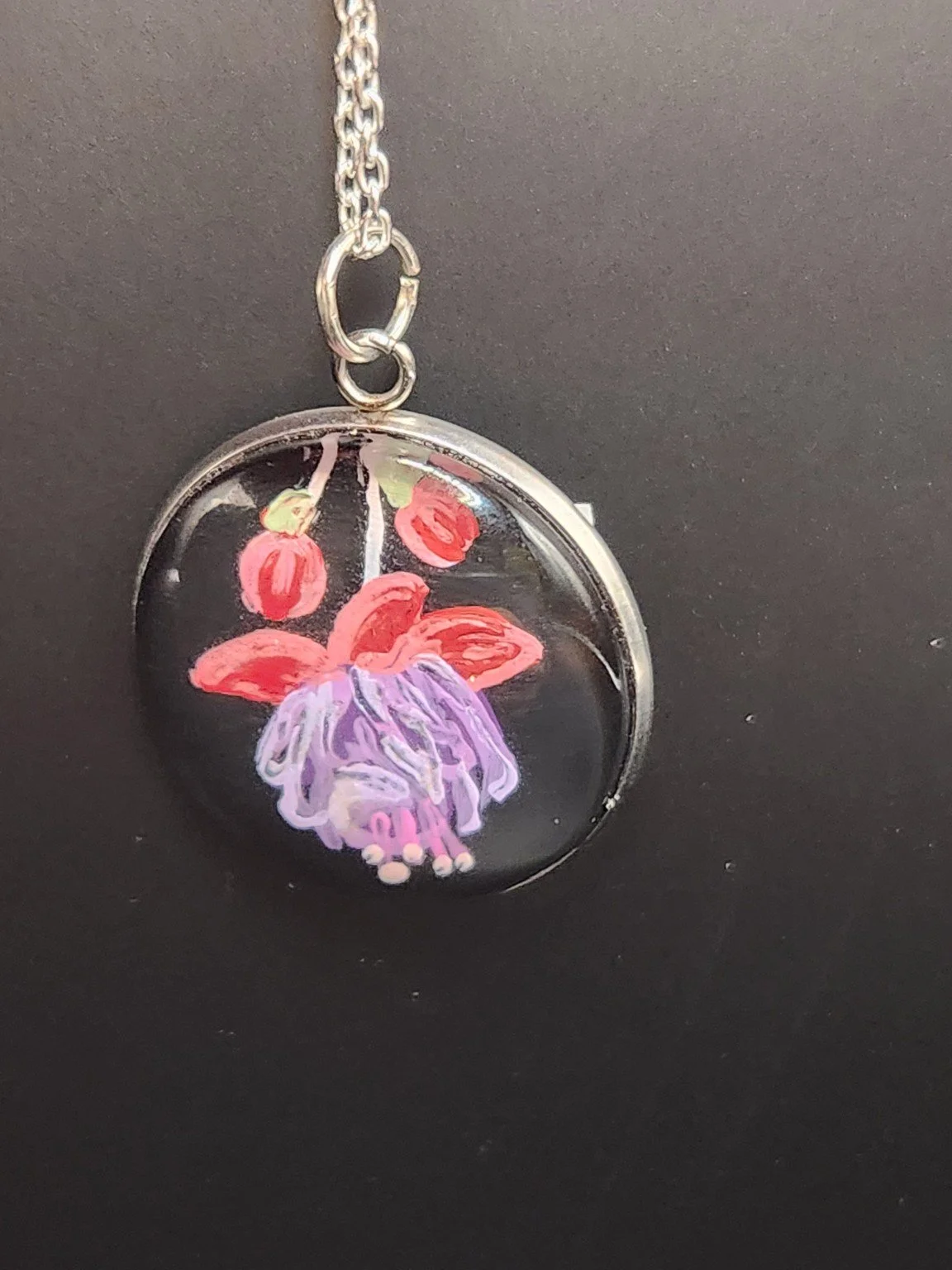 Red and purple fuchsia flower art pendant hanging from a silver-tone chain. Chain not included.
