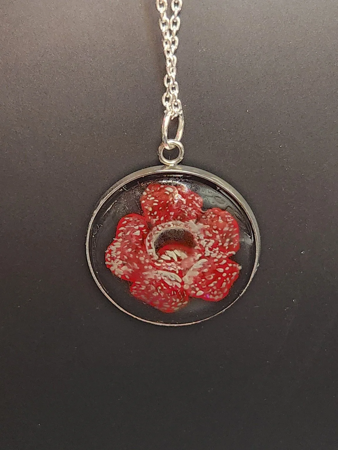 Rafflesia pendant shown on a chain for styling; chain not included.