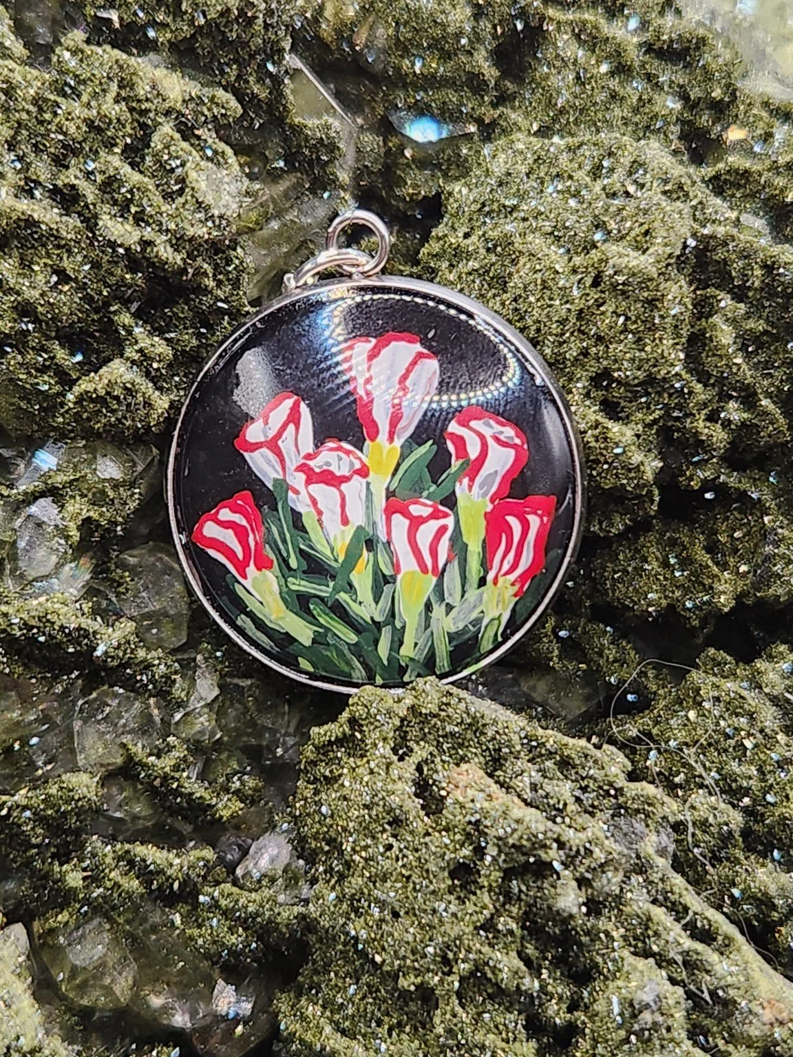 Red and white candy cane sorrel art pendant displayed among green crystals. Crystal display and styling props not included.