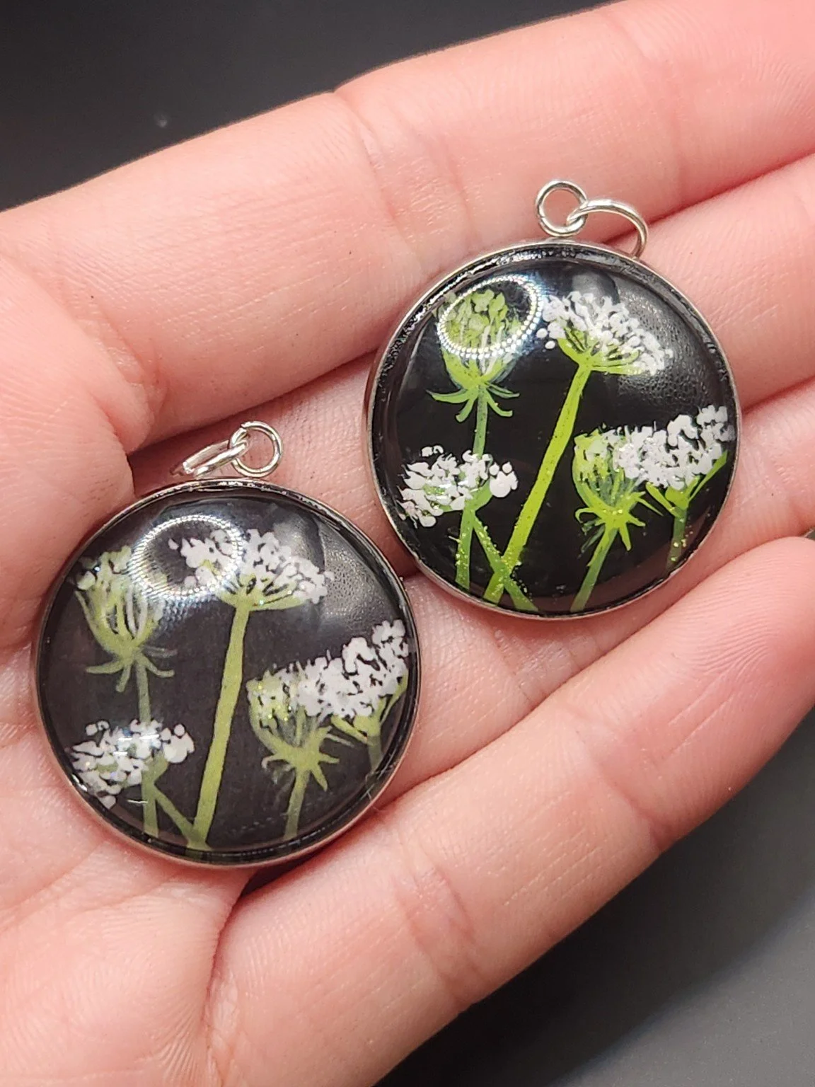 Queen Anne’s lace pendant comparison held in a hand: the hand-painted original is at the top right, and the printed reproduction is at the bottom left.