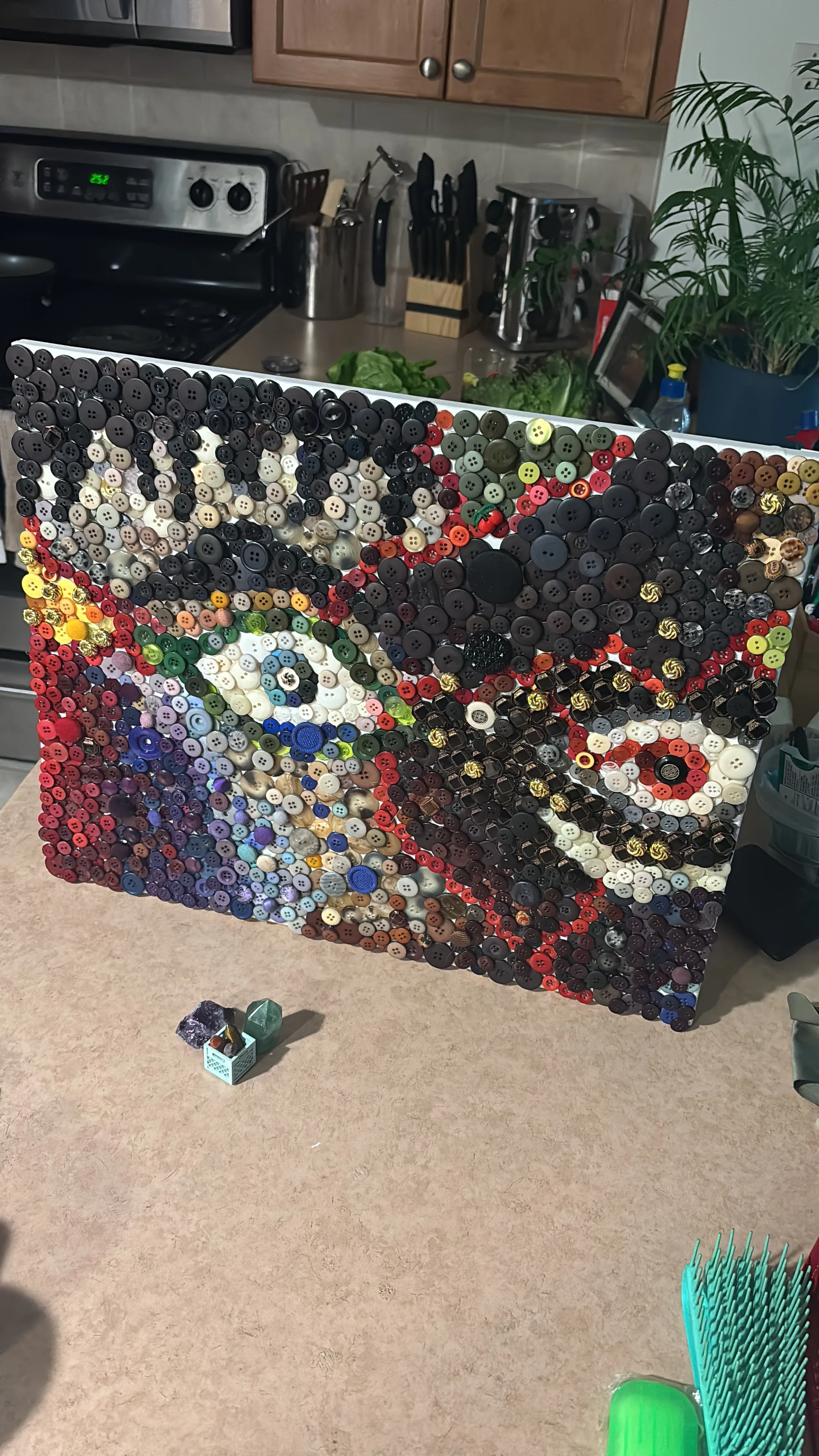 A cardboard box filled with various buttons arranged in a colorful design.