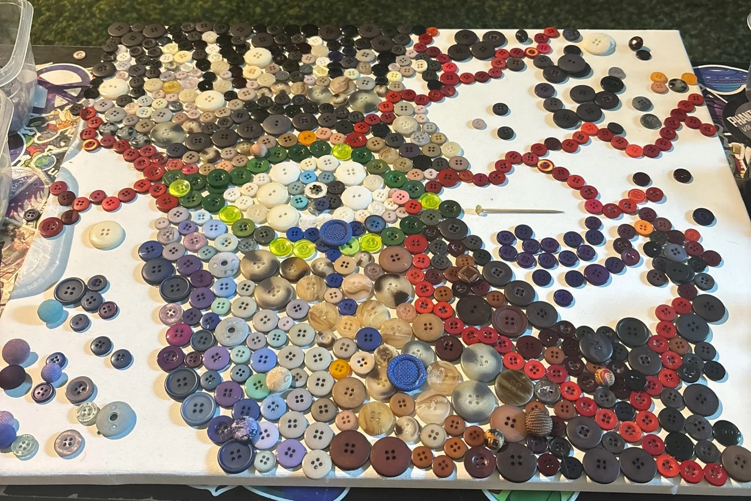 A collection of various buttons in different colors, sizes, and materials spread across a white surface, with some loose buttons scattered around.