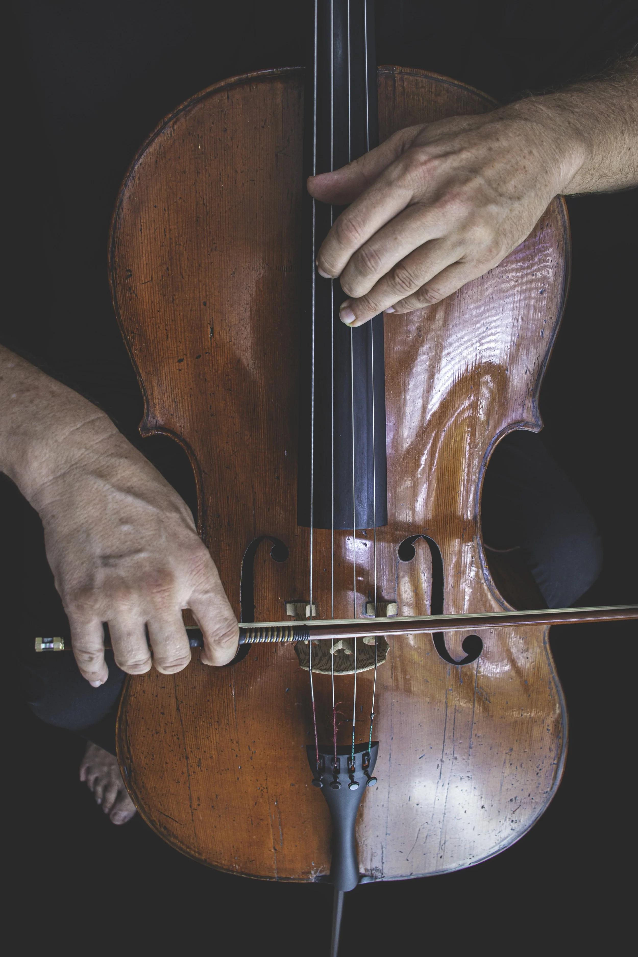 Close-up of a person playing a violin, focusing on their hands and the wooden instrument.