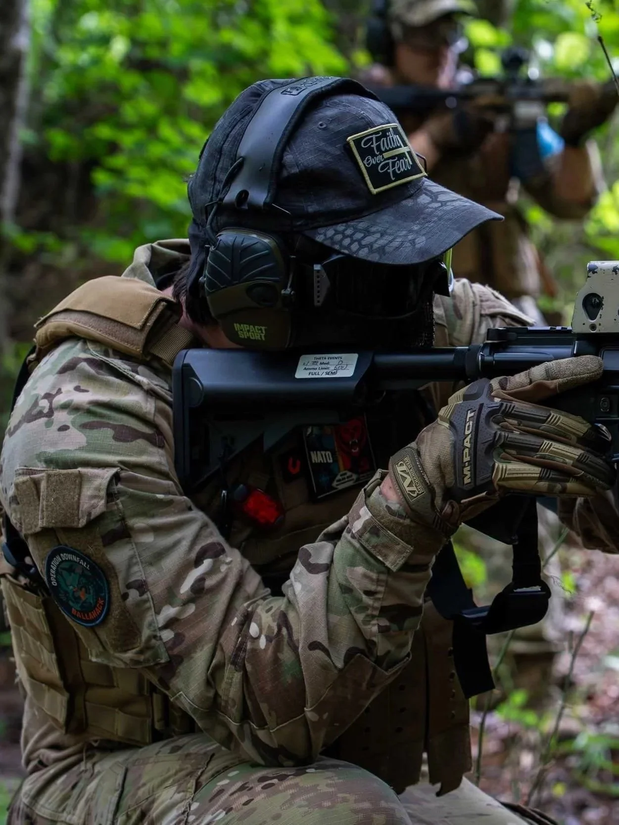 Airsoft player in camouflage gear aiming a rifle in a forest setting.