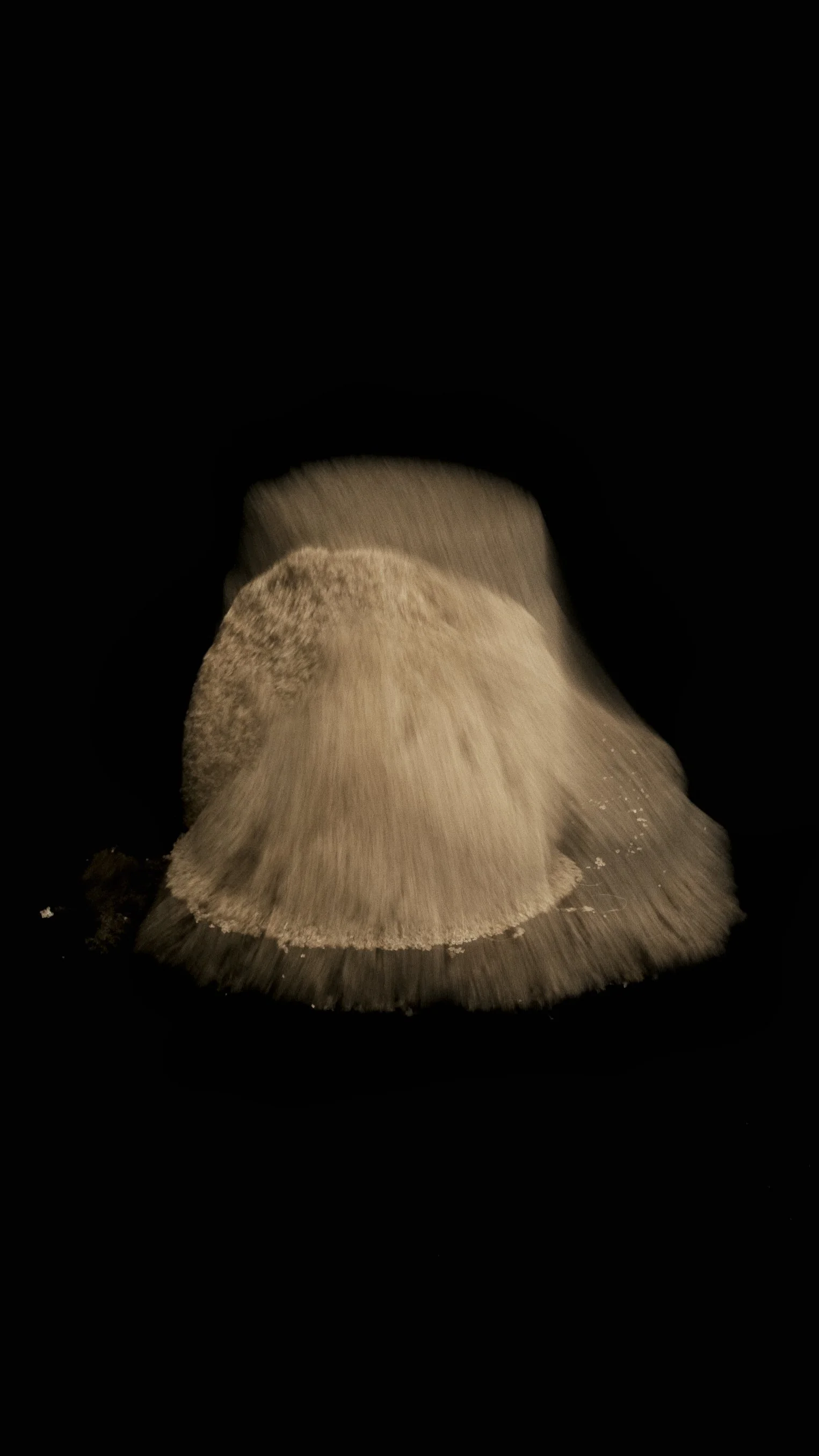 long exposure of sand pile collapsing in neutral palette with black background
