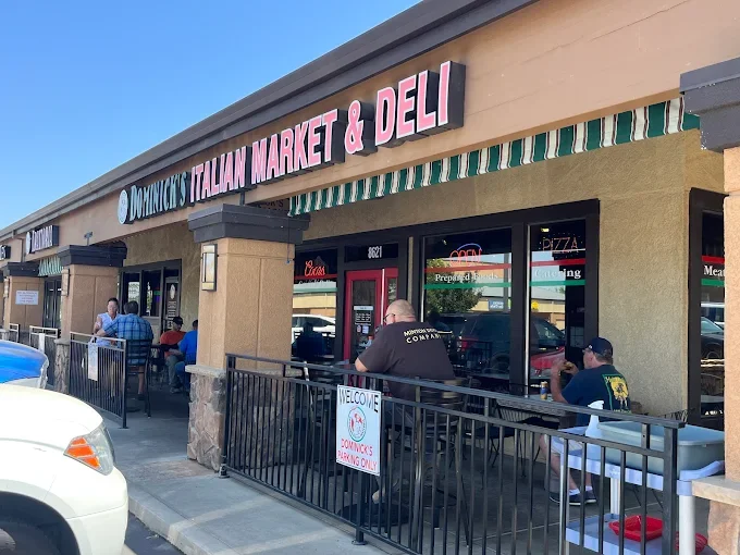 Exterior of Dominic's Italian Market & Deli with customers sitting outside.