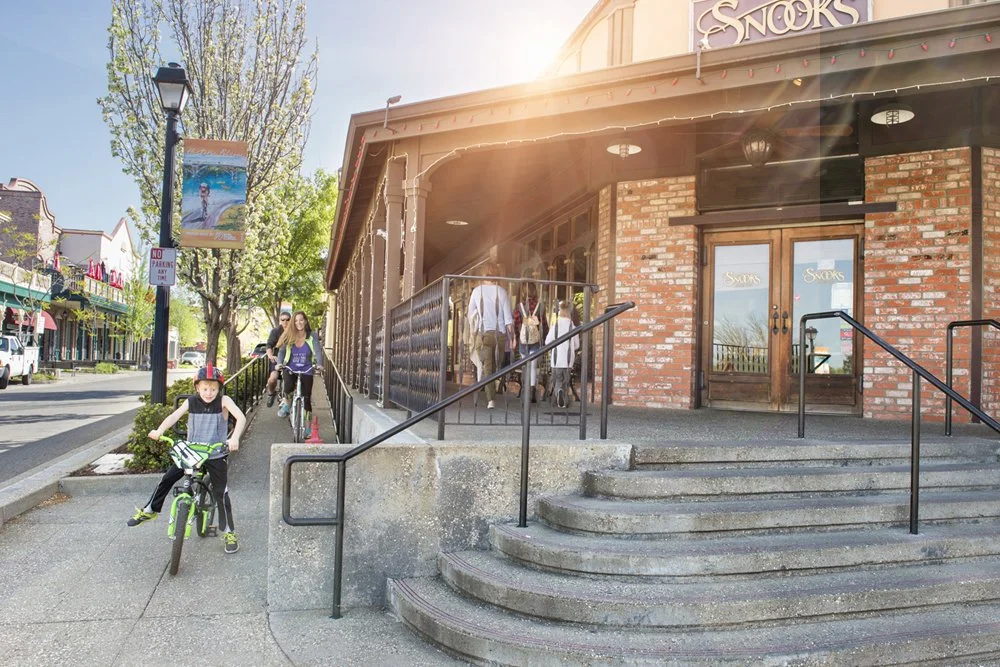 People walking and riding bikes outside a building with the sign 'Snooks' on it.