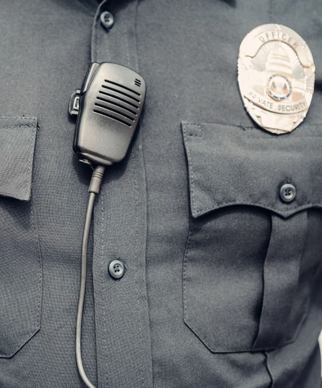Close-up of a police officer's shirt with a badge and a body camera attached to the chest.
