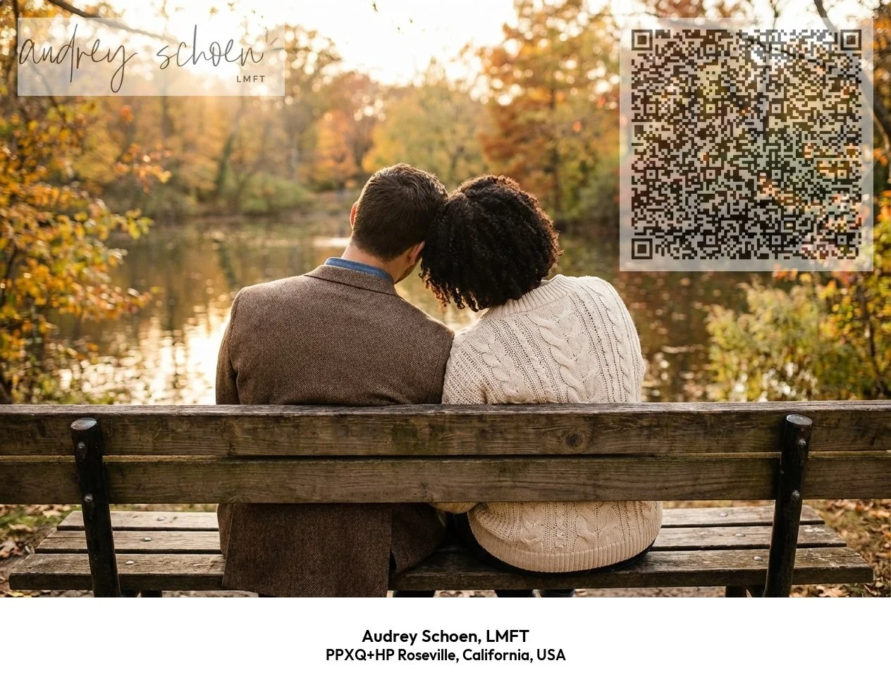 A couple sitting on a wooden bench by a lake during autumn, with trees displaying fall foliage, as the sun sets behind them.