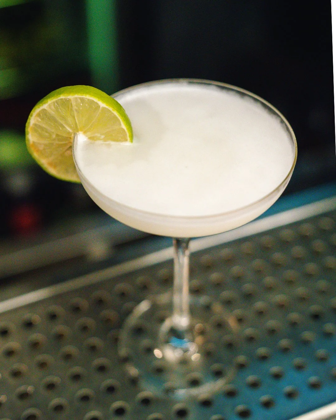 Cocktail in a coupe glass garnished with a lime wedge.