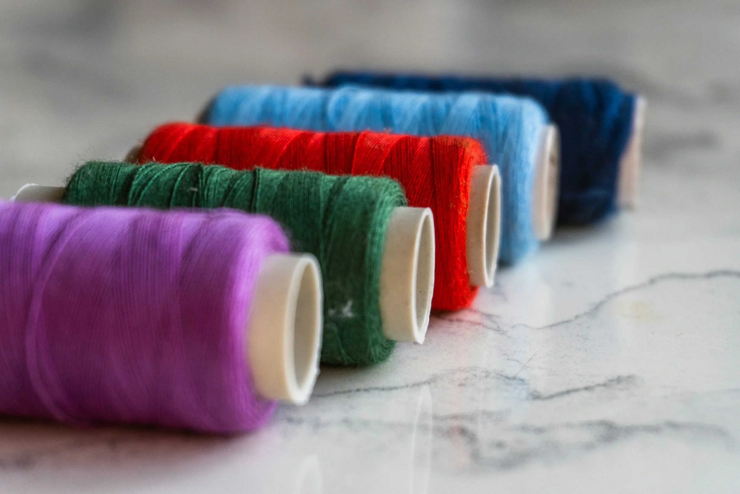 Colorful spools of thread arranged in a row on a light surface.