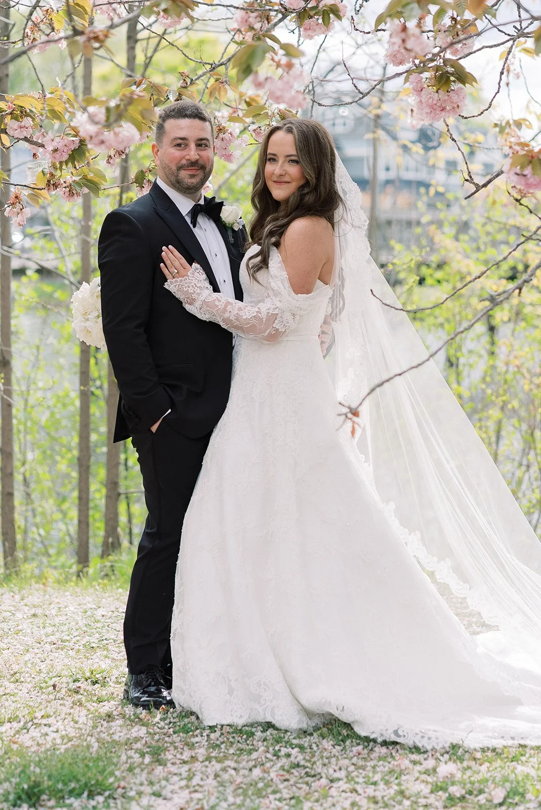 Bride and groom under blooming cherry blossom trees on their spring wedding day, coordinated by Older Sister Events