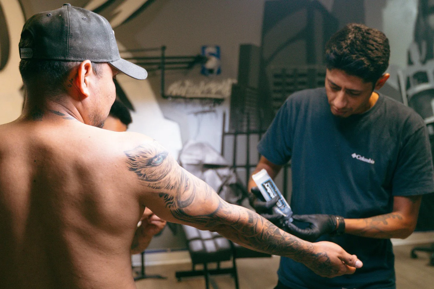 Tattoo artist applies tattoo to a person's arm in a tattoo studio.
