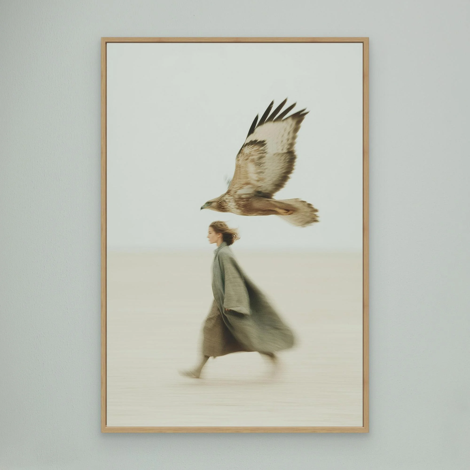 A woman in a gray coat walking past a framed picture of a hawk flying in the sky