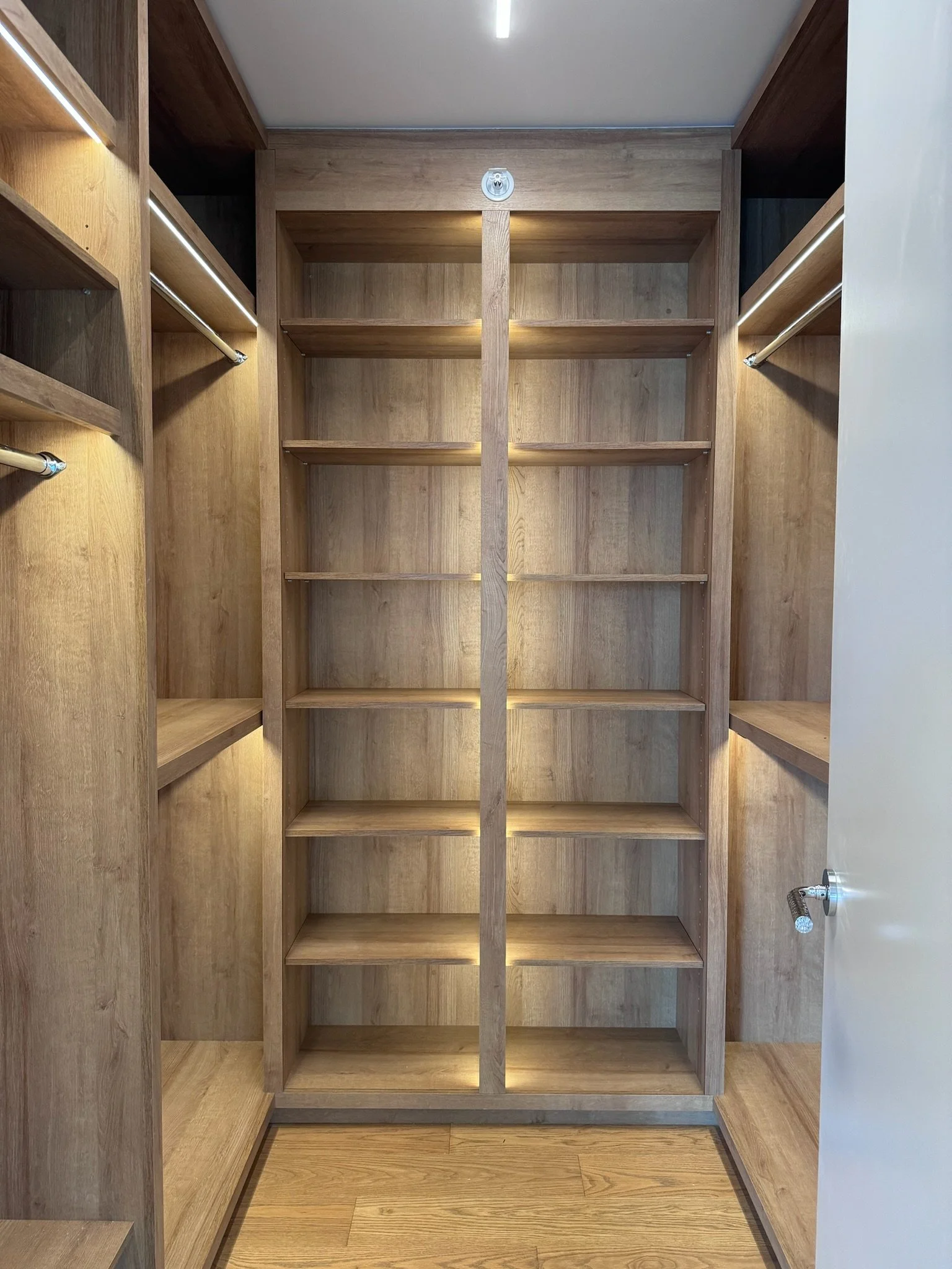 Empty wooden closet with shelves and hanging rods.