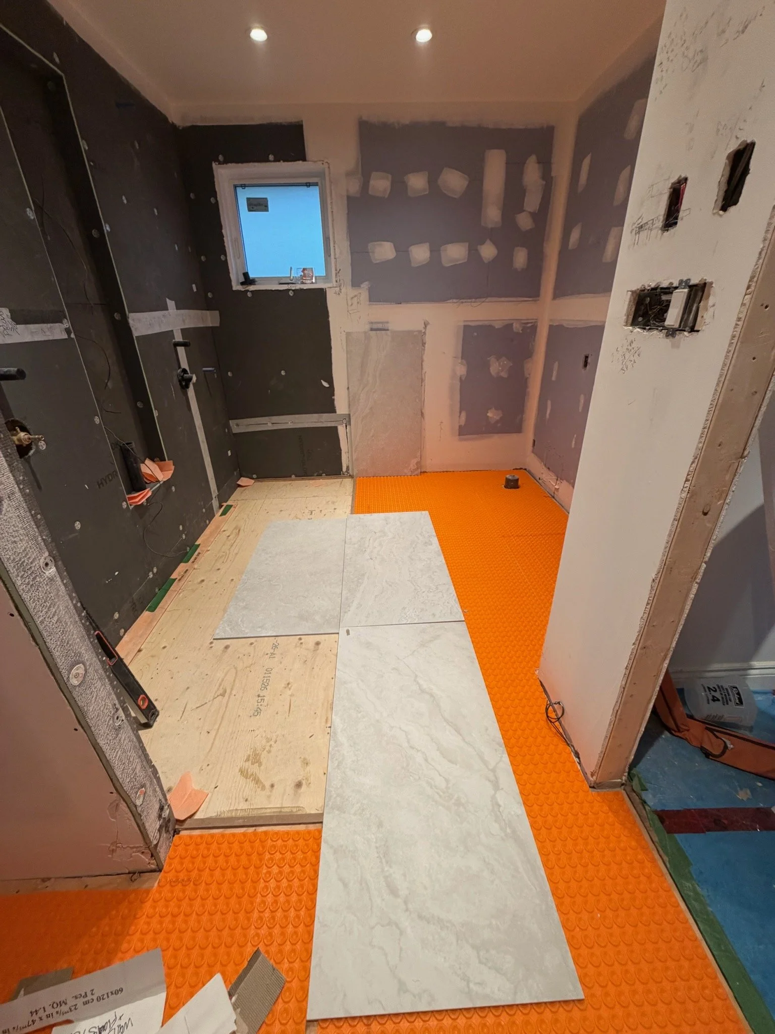 Interior of a room under construction with various flooring tiles and insulation in the walls.