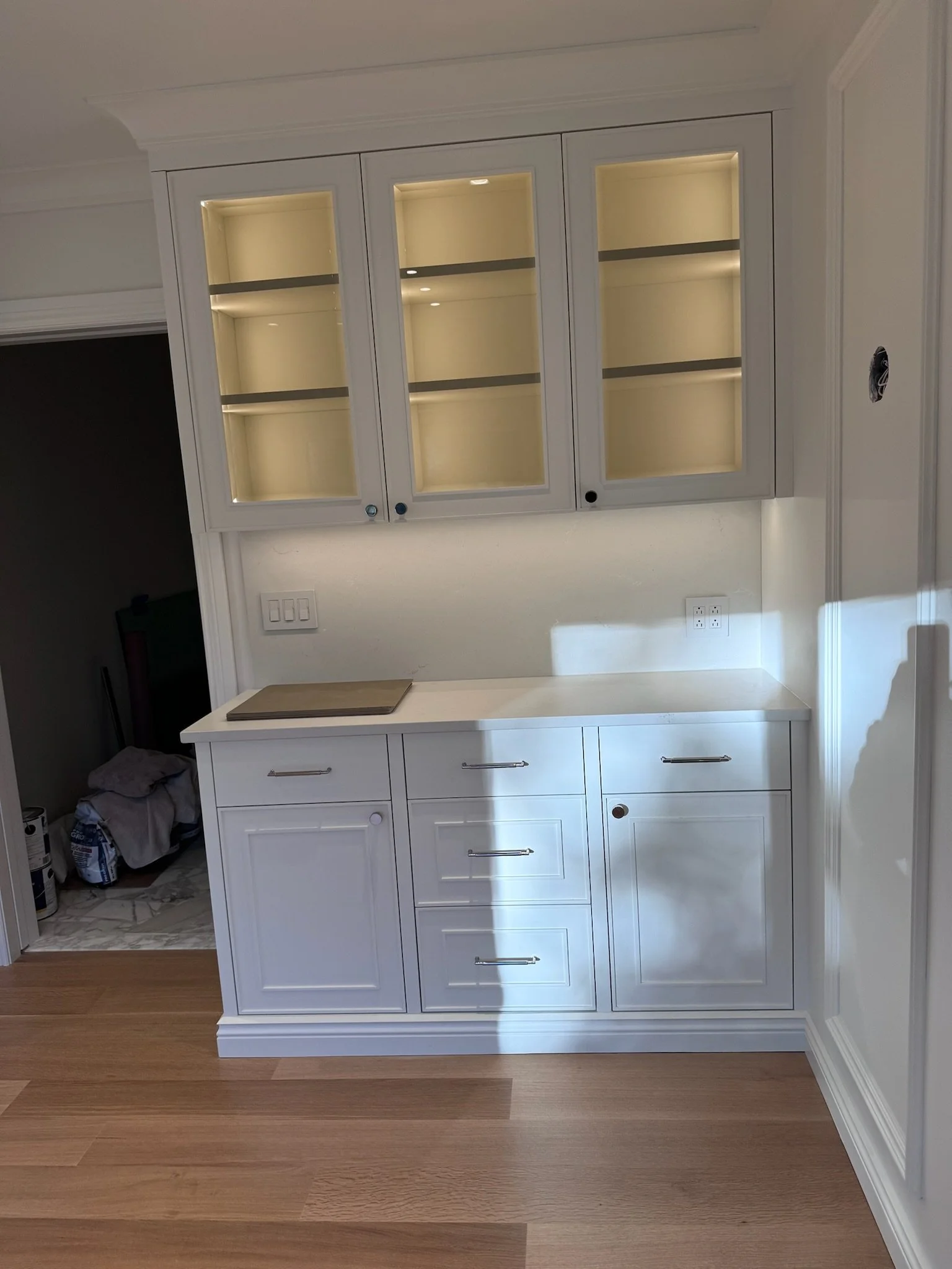 White kitchen cabinet with glass doors and drawers, installed above a white countertop.