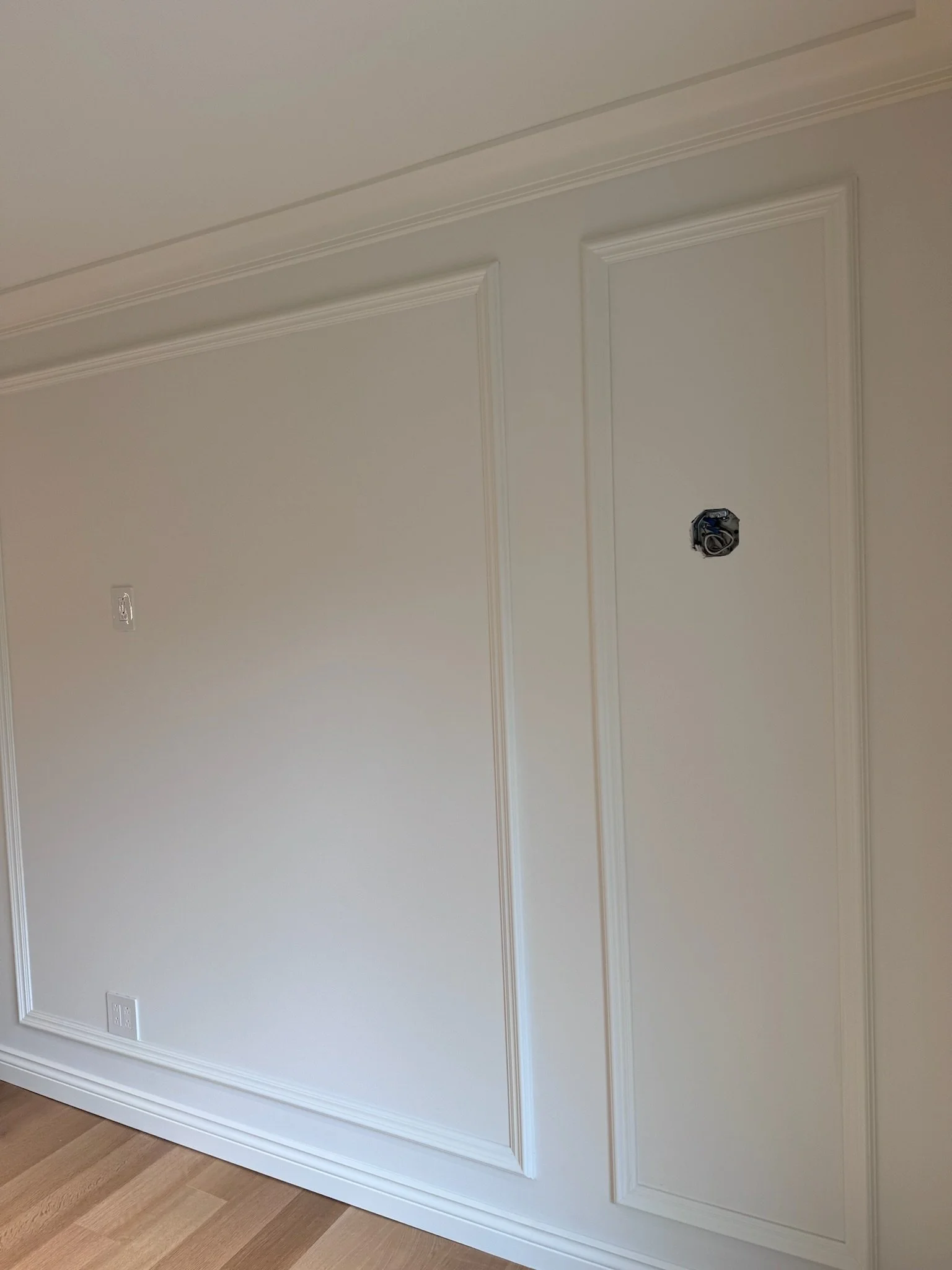Interior wall with decorative molding and electrical outlets, part of a wall interior under renovation.