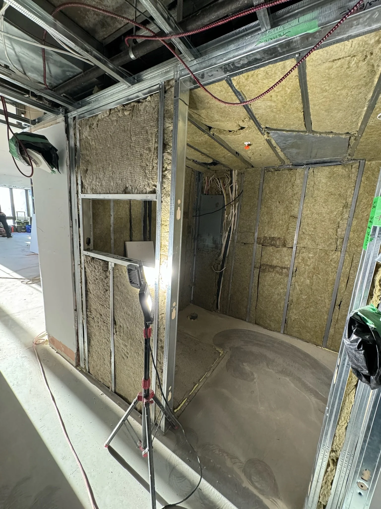 Construction site showing metal framing, insulation, and electrical wiring inside a building under construction.