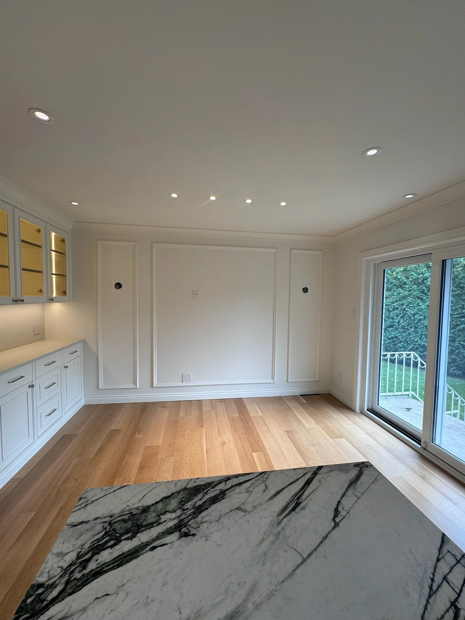 Empty kitchen with white cabinetry, hardwood floors, granite countertop, a sliding glass door leading outside, and a ceiling with multiple recessed lights.