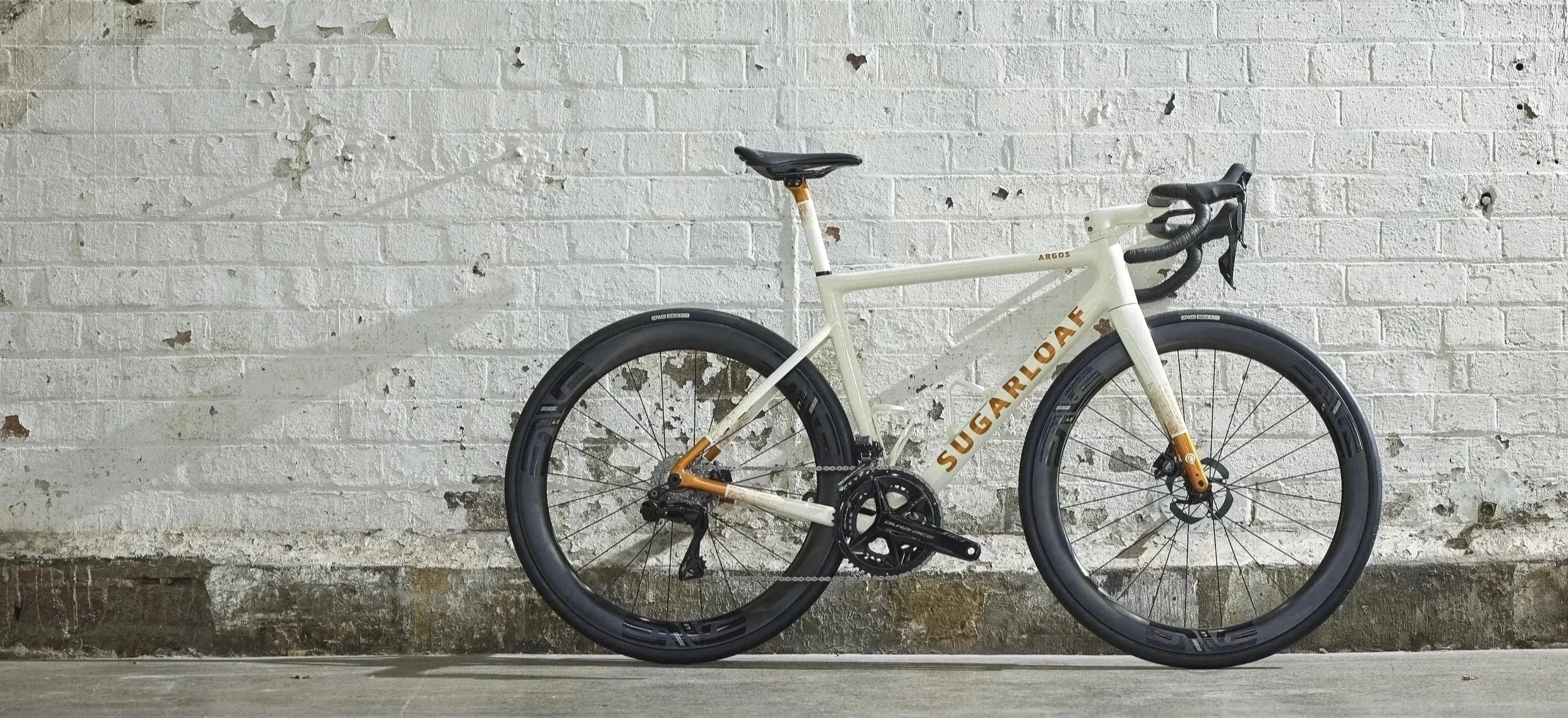 Argos bicycle leaning against a textured white wall with Shimano Dura-ace and envy one piece handlebars