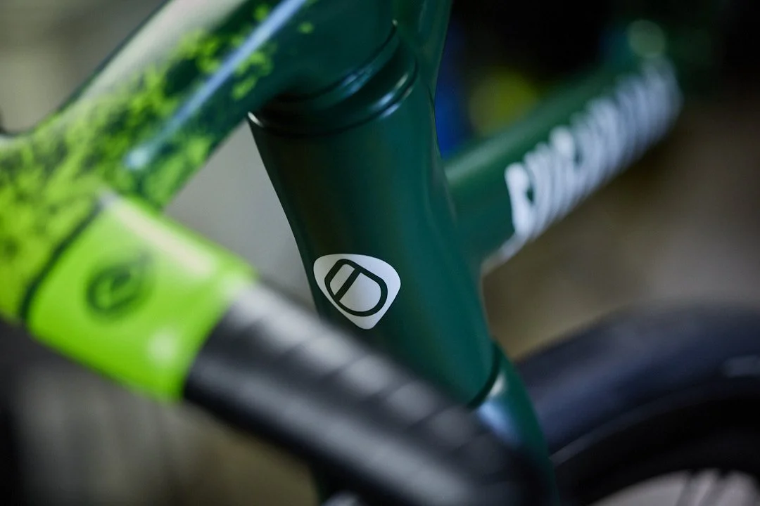 Close up of Sugarloaf logo on head tube of Sugarloaf Heros showing Green paint scheme. Shot through Enve one piece handle bars out of focus in the  foreground