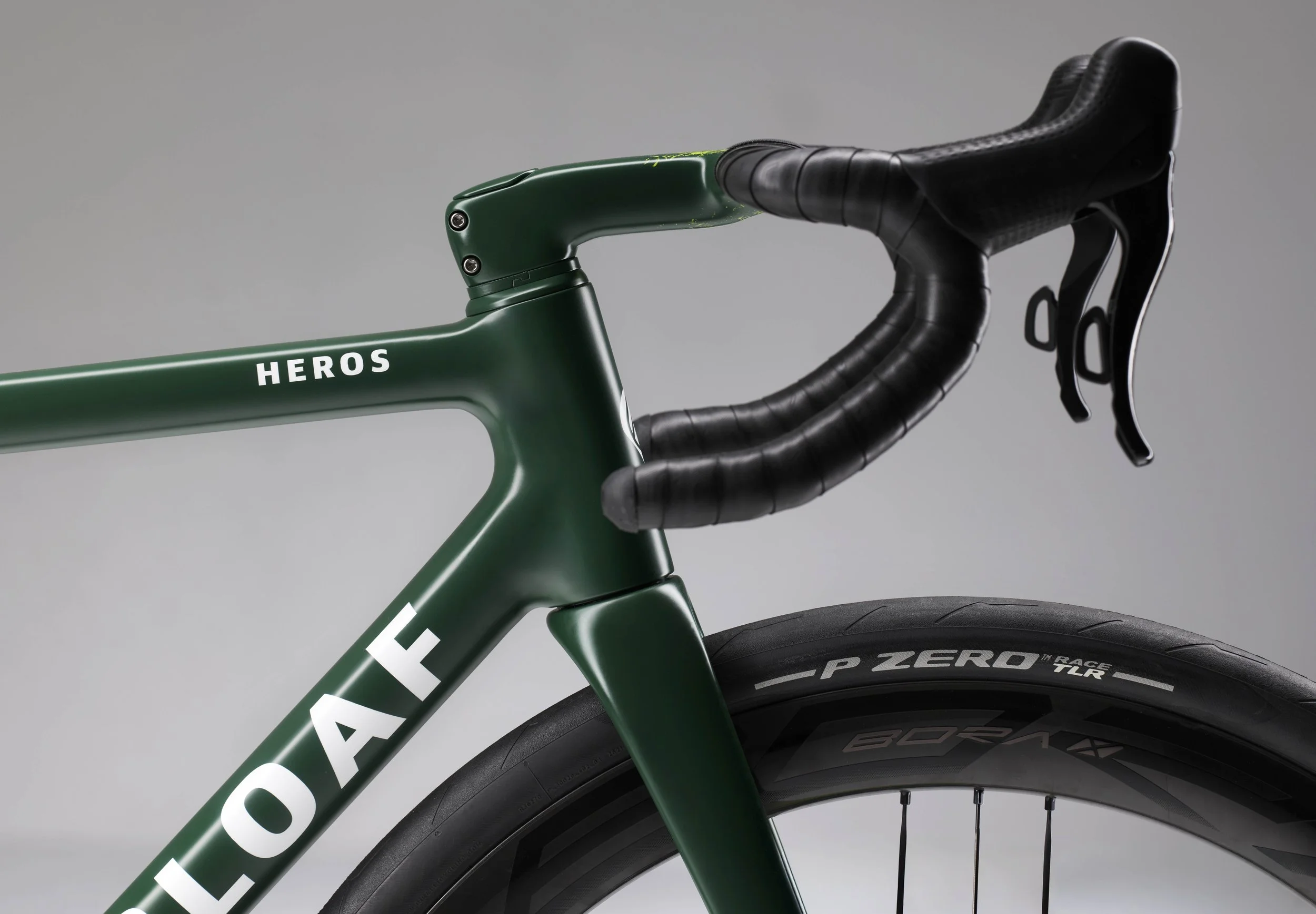 detail image of sugarloaf Heros cockpit side on showing green paint scheme and heros logo, ENVE In-Route handle bars and Campagnolo Bora wheels with Pirelli P Zero trees