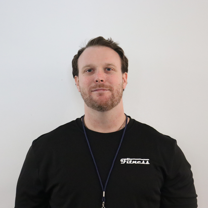 A man with short dark hair and a beard, wearing a black shirt and a lanyard, standing in front of a white background.
