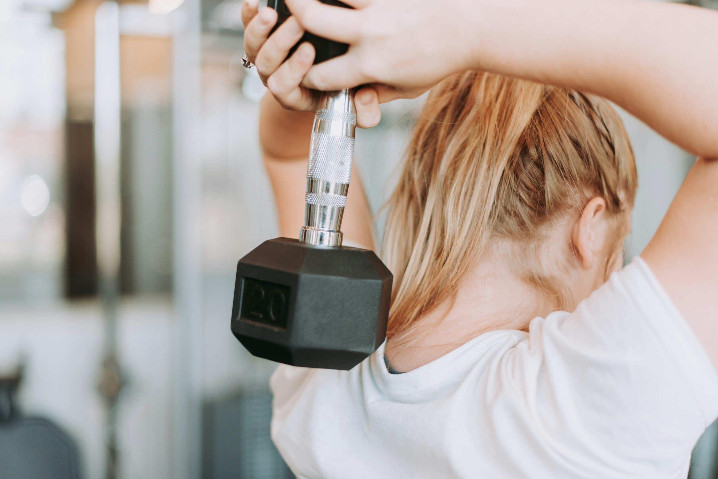 A hairdresser is using a handheld device to cut or style a woman's blonde hair in a salon.